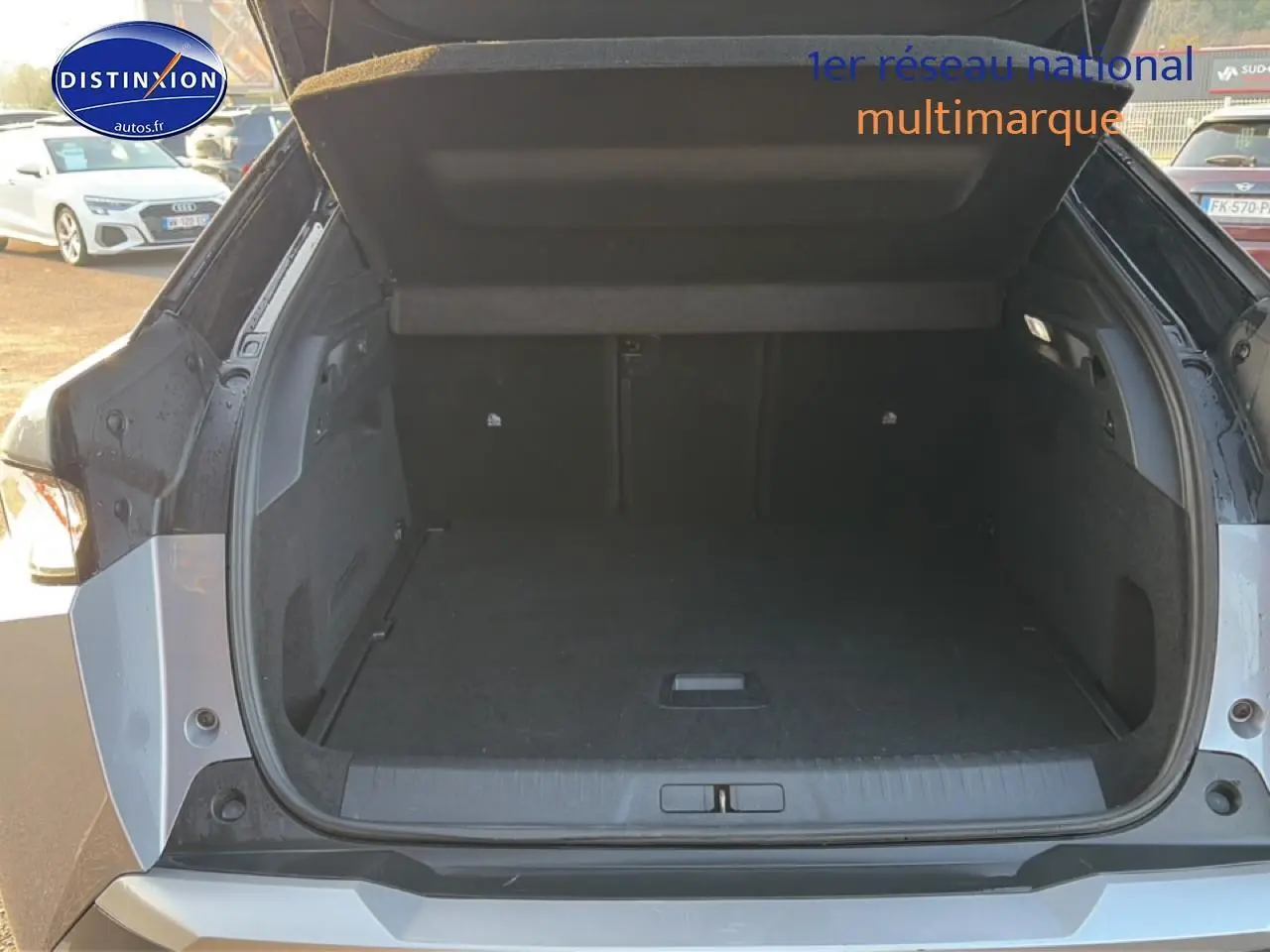 Coffre ouvert vu de l'arrière d'un Peugeot 3008 gris 2025, montrant un espace de chargement spacieux et propre.