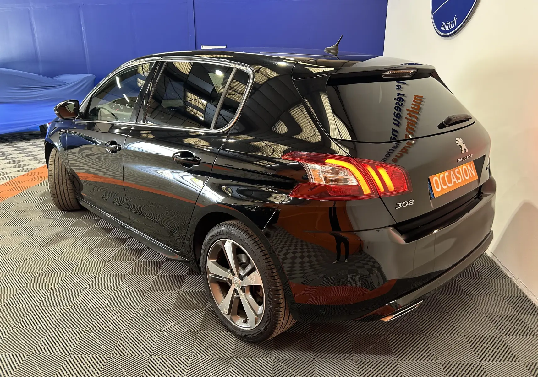 Peugeot 308 noire vue en 3/4 arrière droit, avec feux arrière allumés et plaque "OCCASION" visible.
