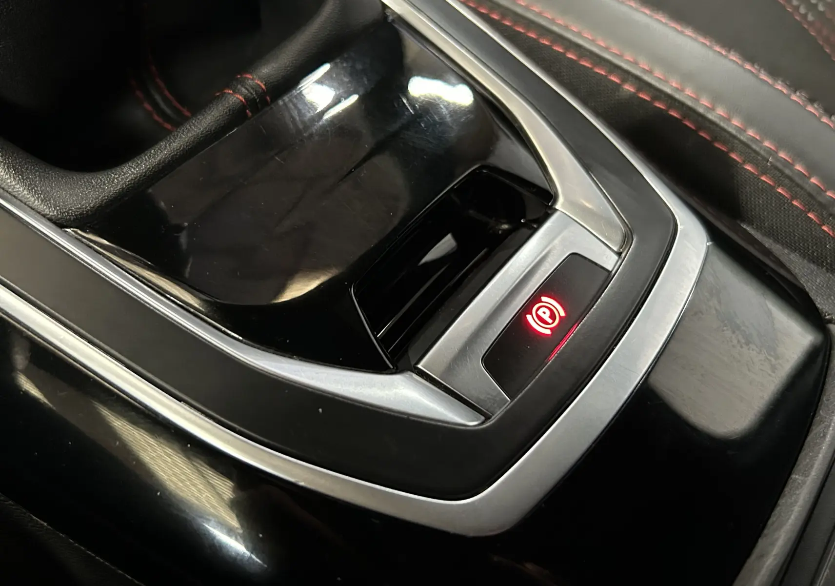 Gros plan sur la console centrale noire de la Peugeot 308 GT Line 2017, avec frein à main électronique rouge allumé.
