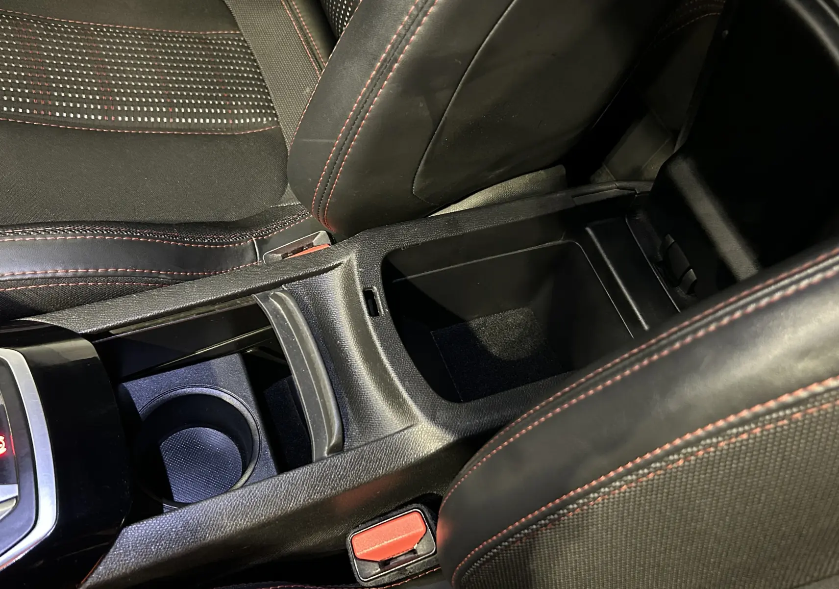 Vue rapprochée de la console centrale noire avec rangement ouvert et surpiqûres rouges des sièges Peugeot 308 GT Line 2017.