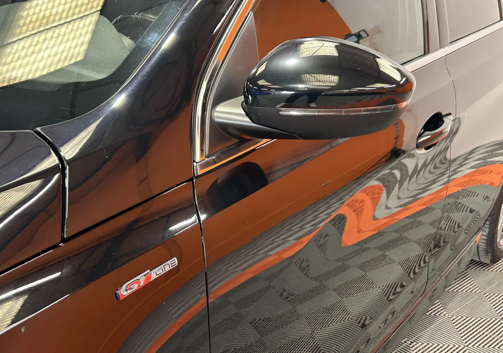 Vue rapprochée côté gauche de la Peugeot 308 GT Line noire, mettant en valeur le rétroviseur et le logo GT Line sur la portière.