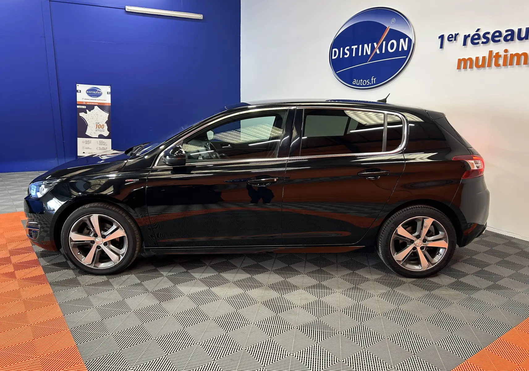 Peugeot 308 noir vue de profil côté gauche dans un showroom avec jantes alliage et toit ouvrant.