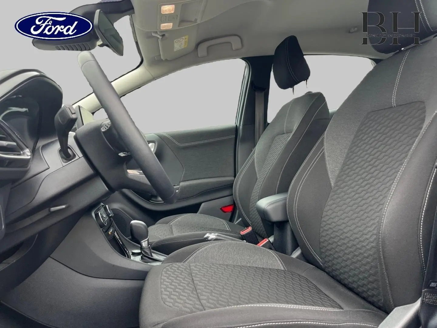 Vue intérieure côté conducteur du Ford Puma 2023, sièges tissu noir Kasbah avec surpiqûres blanches et accoudoir central.