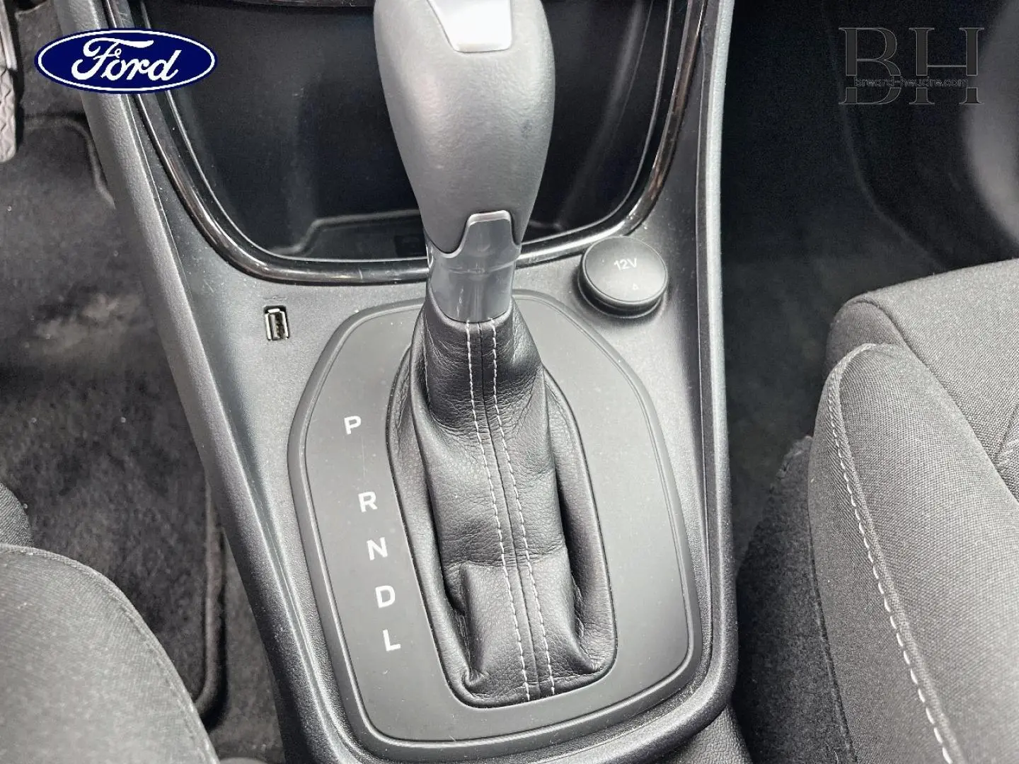 Gros plan sur la commande de la boîte automatique noire du Ford Puma 2023, avec tissu de siège gris visible à droite.