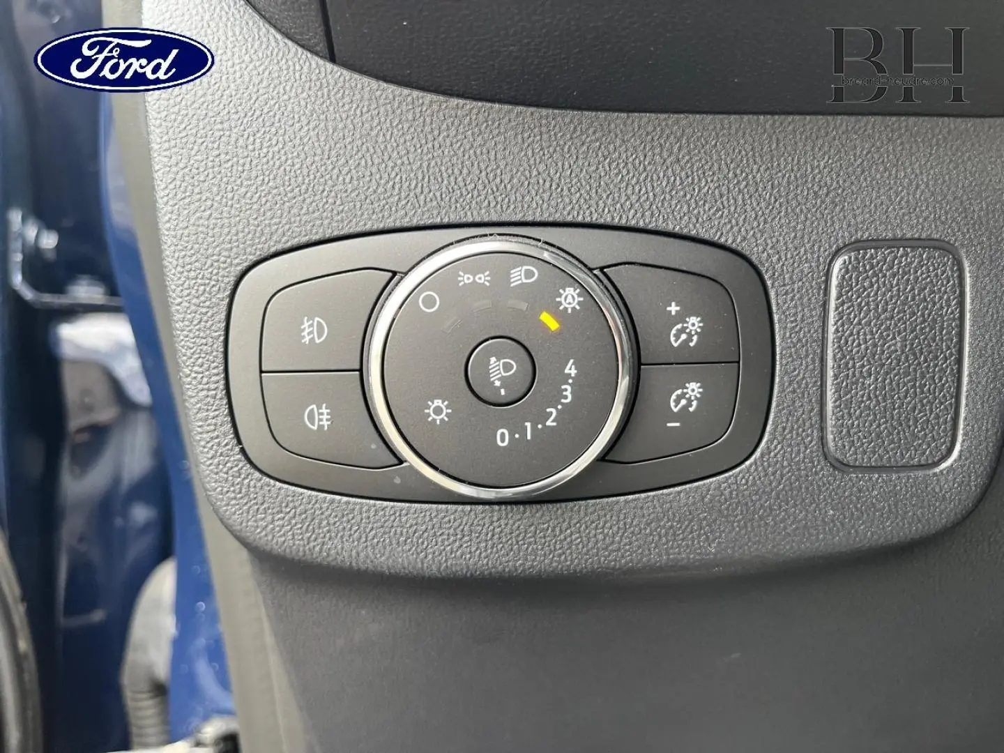 Gros plan sur la molette de réglage des phares du Ford Puma bleu, avec commandes d’éclairage et luminosité.