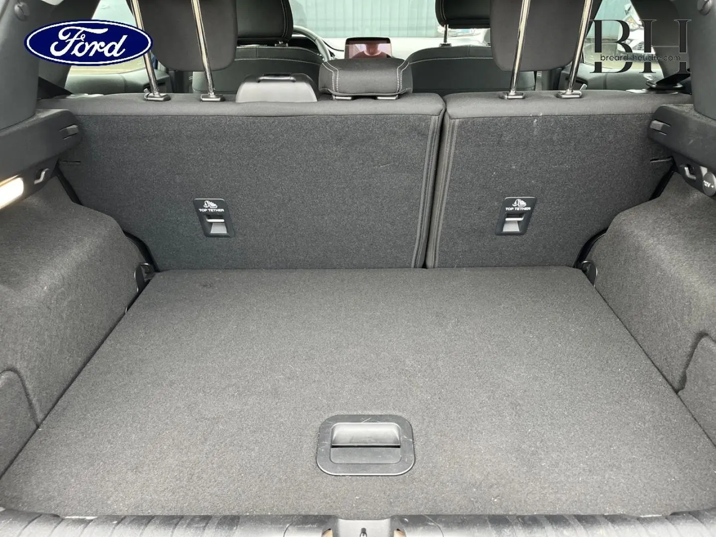 Vue du coffre arrière ouvert du Ford Puma 2023, intérieur tissu noir avec banquette rabattable et ancrages Top Tether.