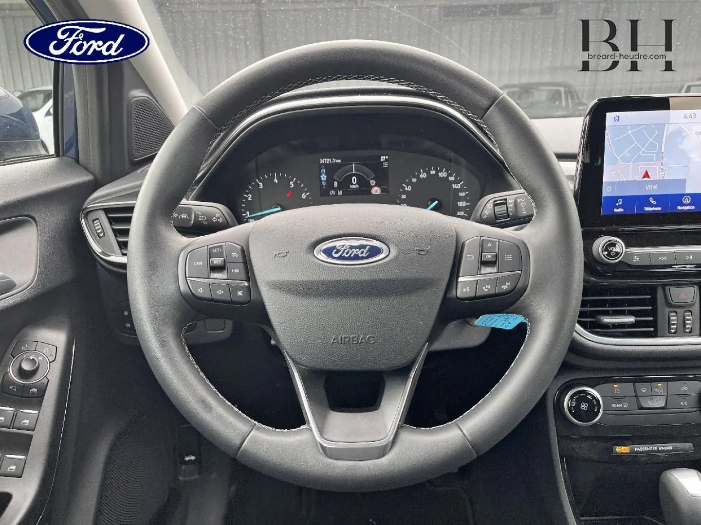 Vue intérieure centrée sur le volant multifonction du Ford Puma bleu avec tableau de bord et écran tactile visible.