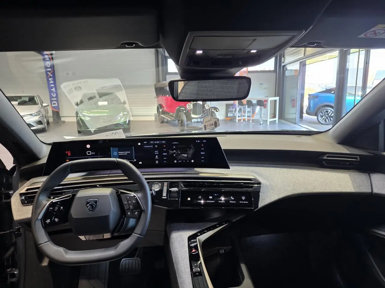 Intérieur Peugeot 3008 2025 vue de face sur le tableau de bord avec volant compact noir et écran panoramique incurvé.