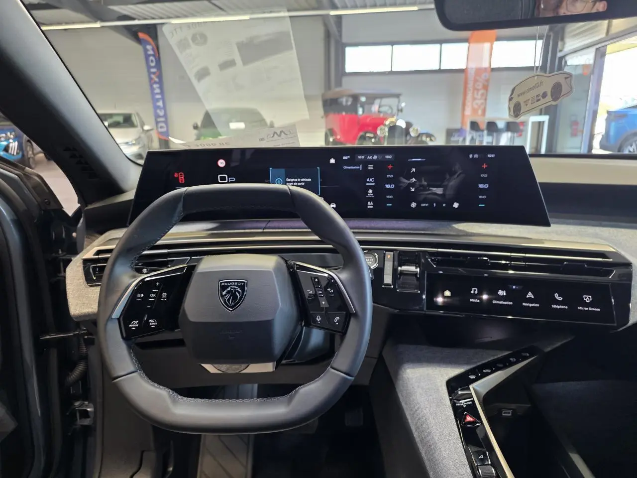 Intérieur du Peugeot 3008 2025 vue de face sur le volant compact et l'écran incurvé panoramique noir.