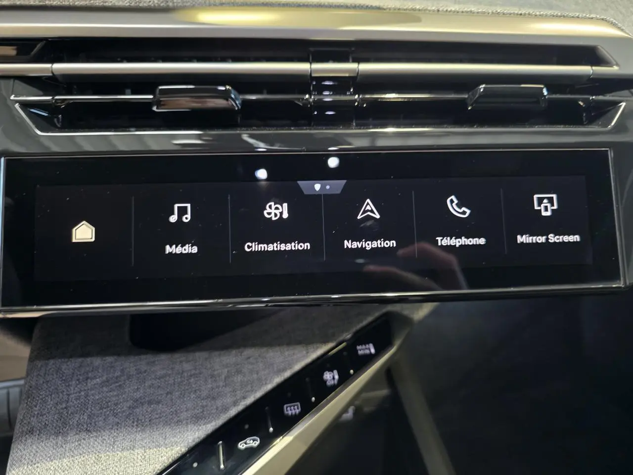 Écran tactile central noir brillant du Peugeot 3008 2025 avec commandes multimédia et climatisation, planche de bord tissu gris.