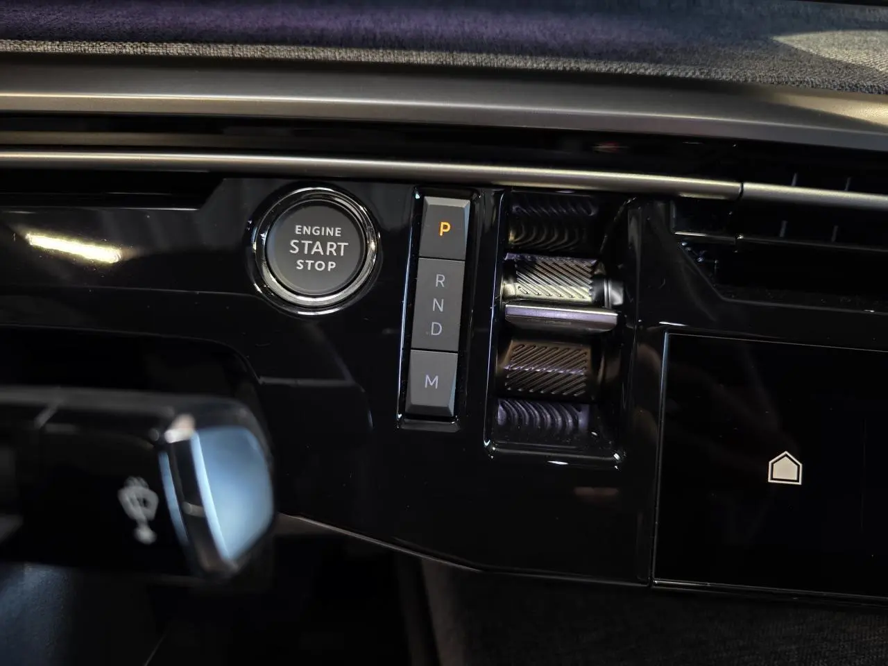 Détail de la console centrale noire brillante du Peugeot 3008 2025 avec bouton start/stop et sélecteur de boîte auto.