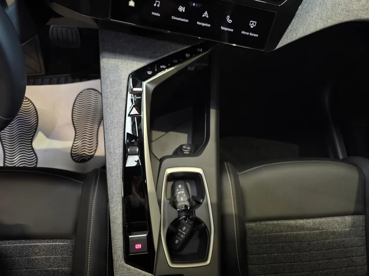 Vue plongeante sur la console centrale du Peugeot 3008 2025, avec clés, sellerie tissu et cuir noir.