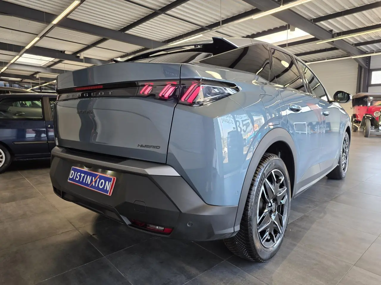 Vue 3/4 arrière droite du Peugeot 3008 hybride bleu clair avec jantes alliage noires et feux arrière LED 3 griffes.