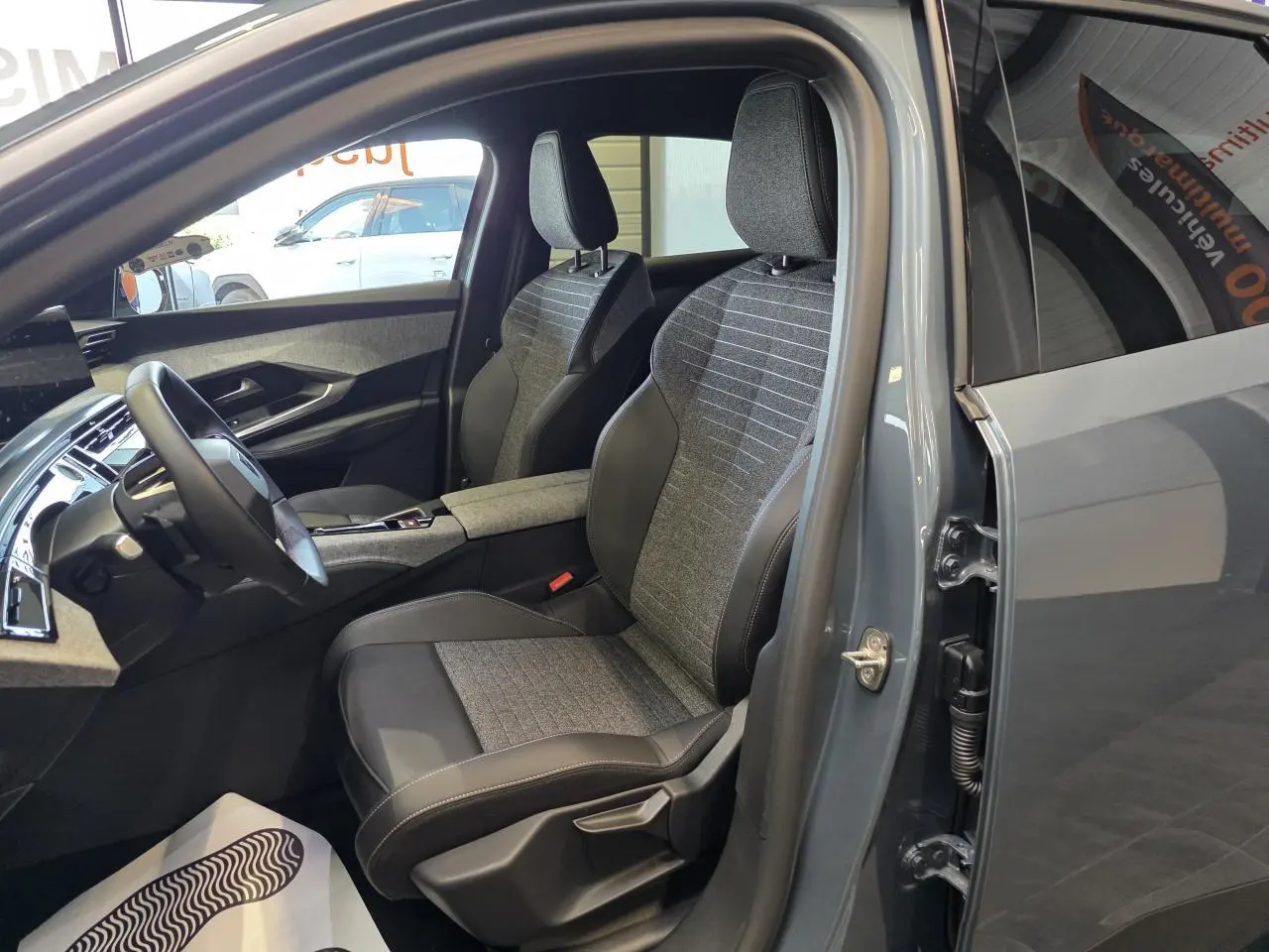 Vue intérieure côté conducteur du Peugeot 3008 2025 bleu clair, avec sièges tissu et cuir bicolore gris et noir.