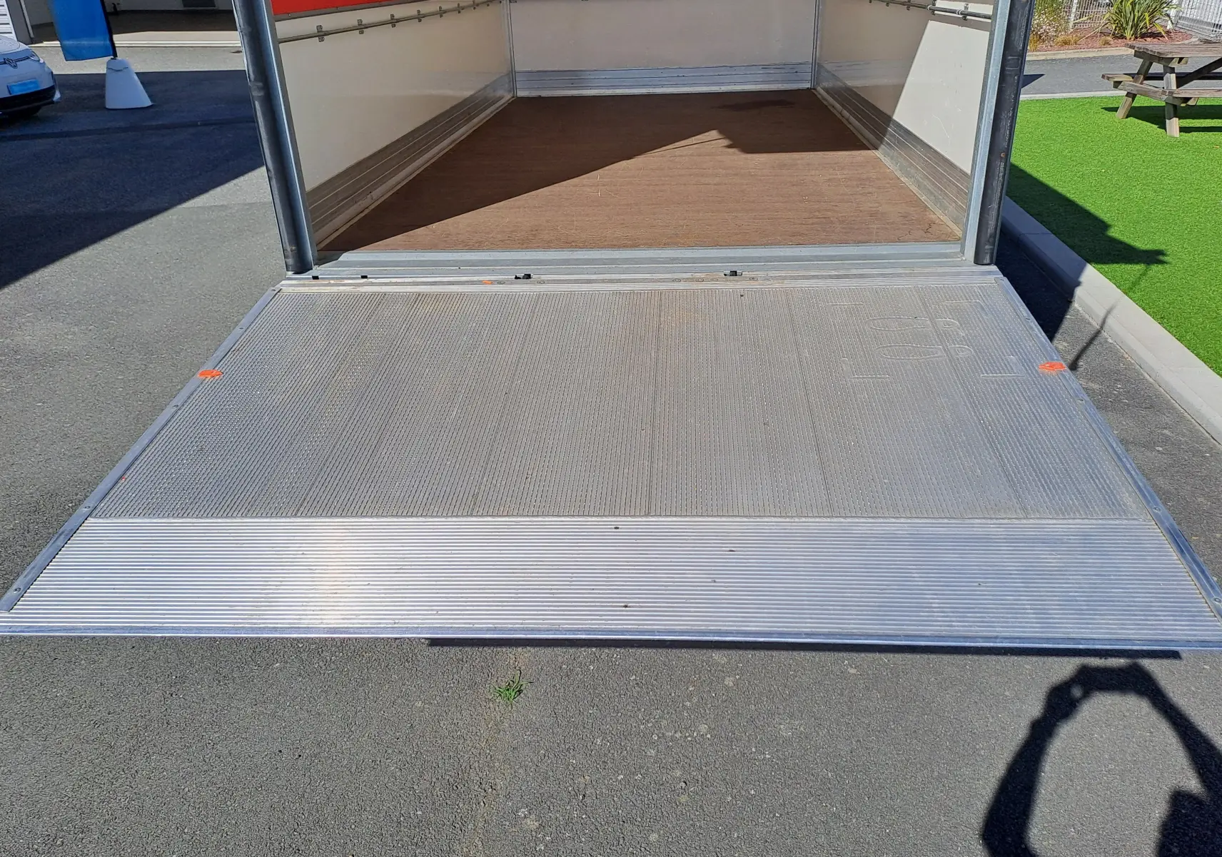 Vue arrière du Nissan Interstar châssis cabine blanc 2024 avec porte arrière ouverte et plancher en bois visible.
