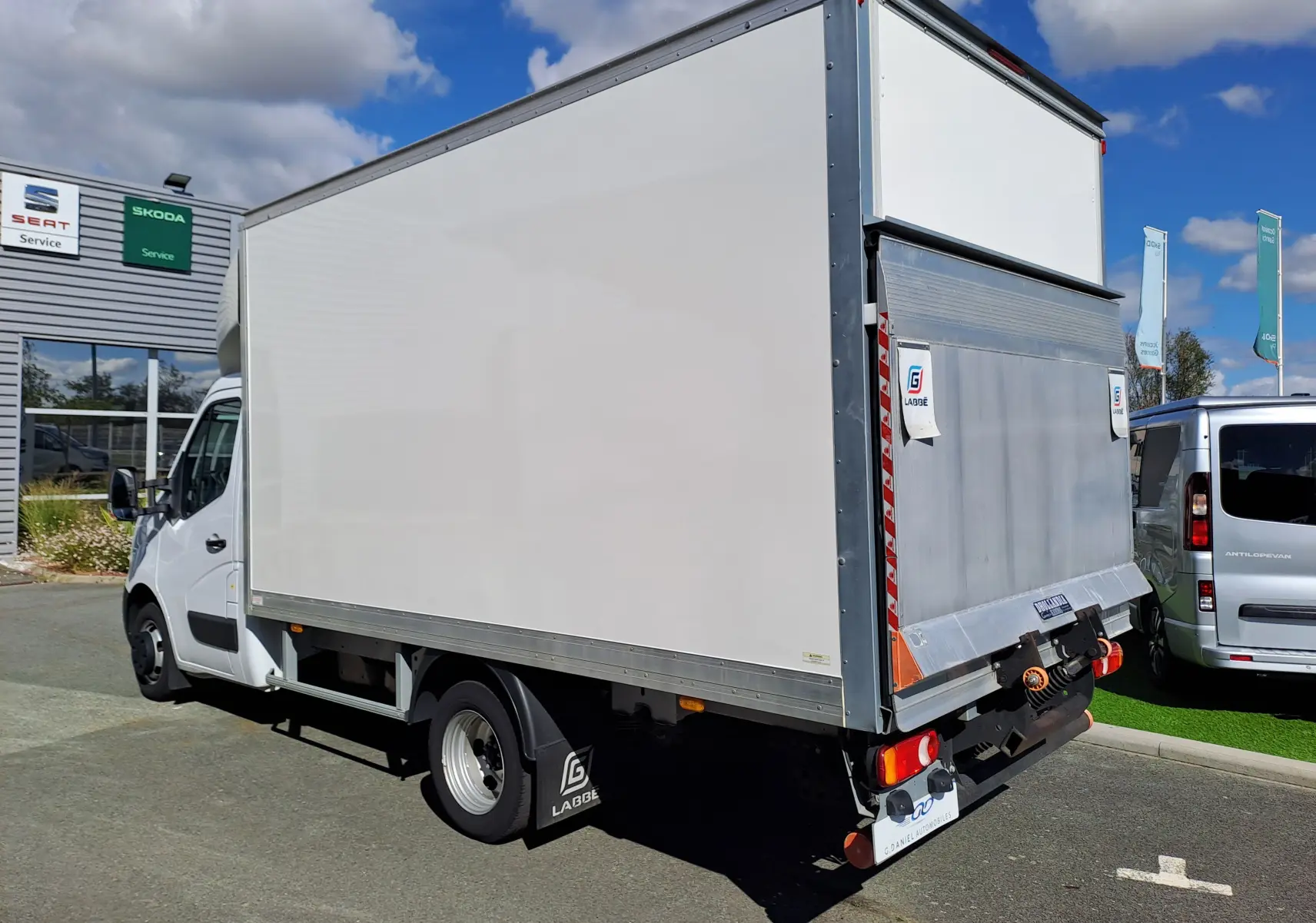 Vue 3/4 arrière droite du Nissan Interstar châssis cabine blanc 2024 avec hayon élévateur métallique fermé.