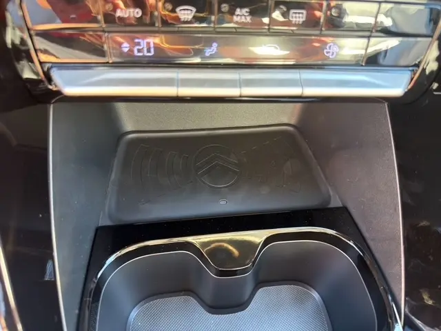 Vue rapprochée de la zone de recharge par induction avec logo Citroën, située devant les commandes de climatisation.