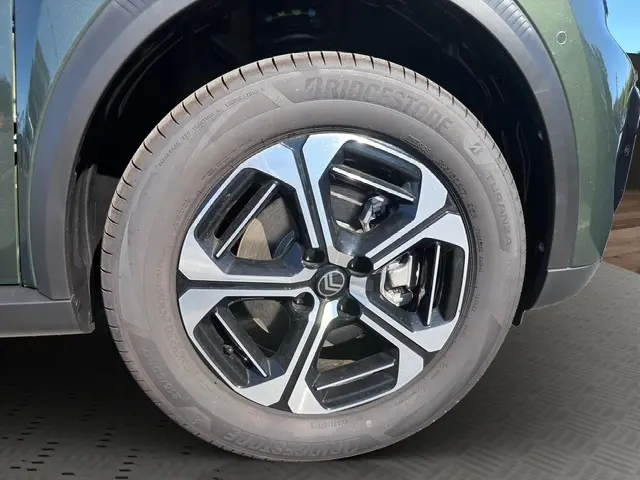Gros plan sur la roue avant gauche du Citroën C3 Aircross hybride vert, avec jante alliage bicolore et pneu Bridgestone.