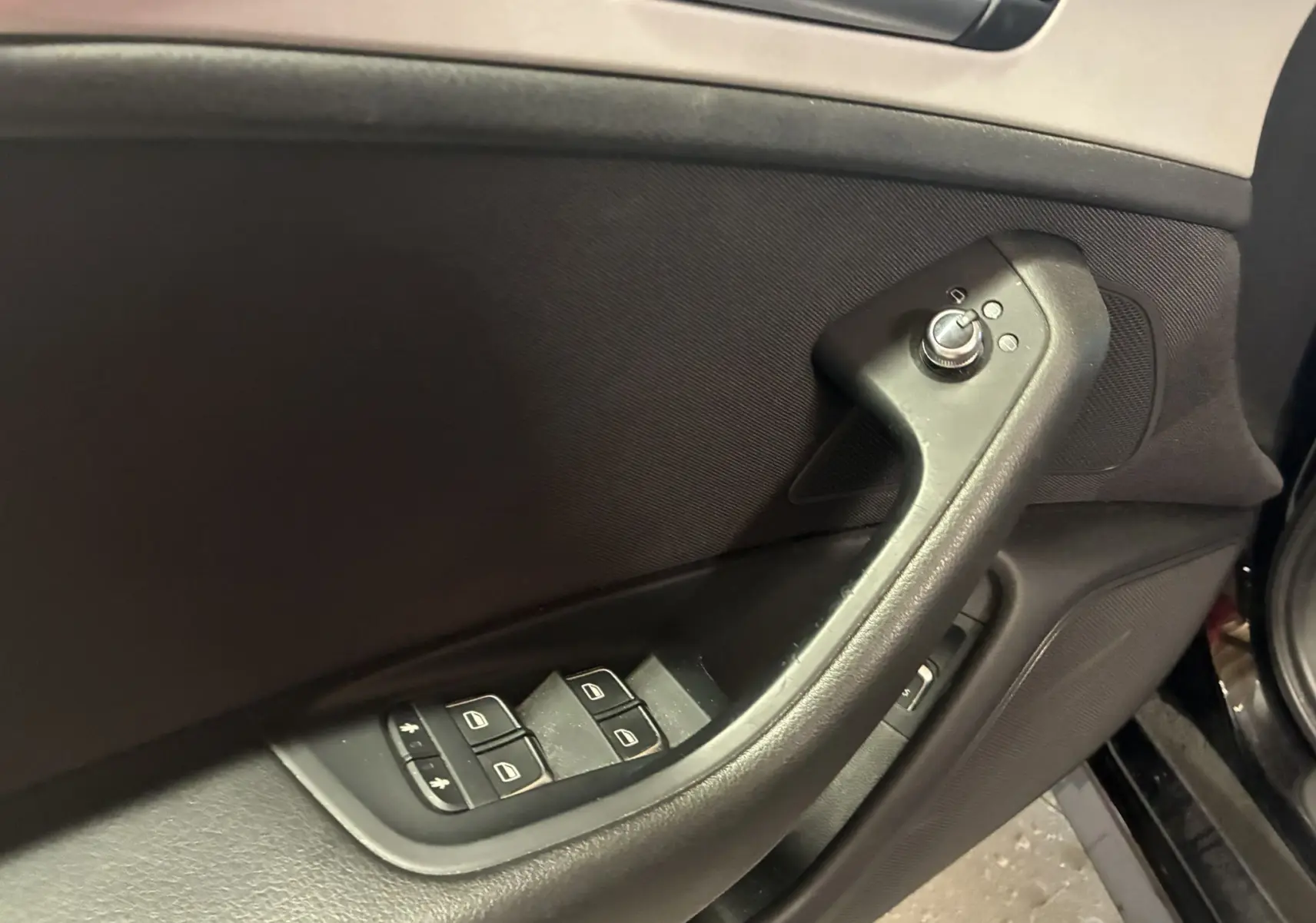 Gros plan sur la commande des vitres et rétroviseurs côté conducteur d'une Audi A6 Avant noire de 2017.