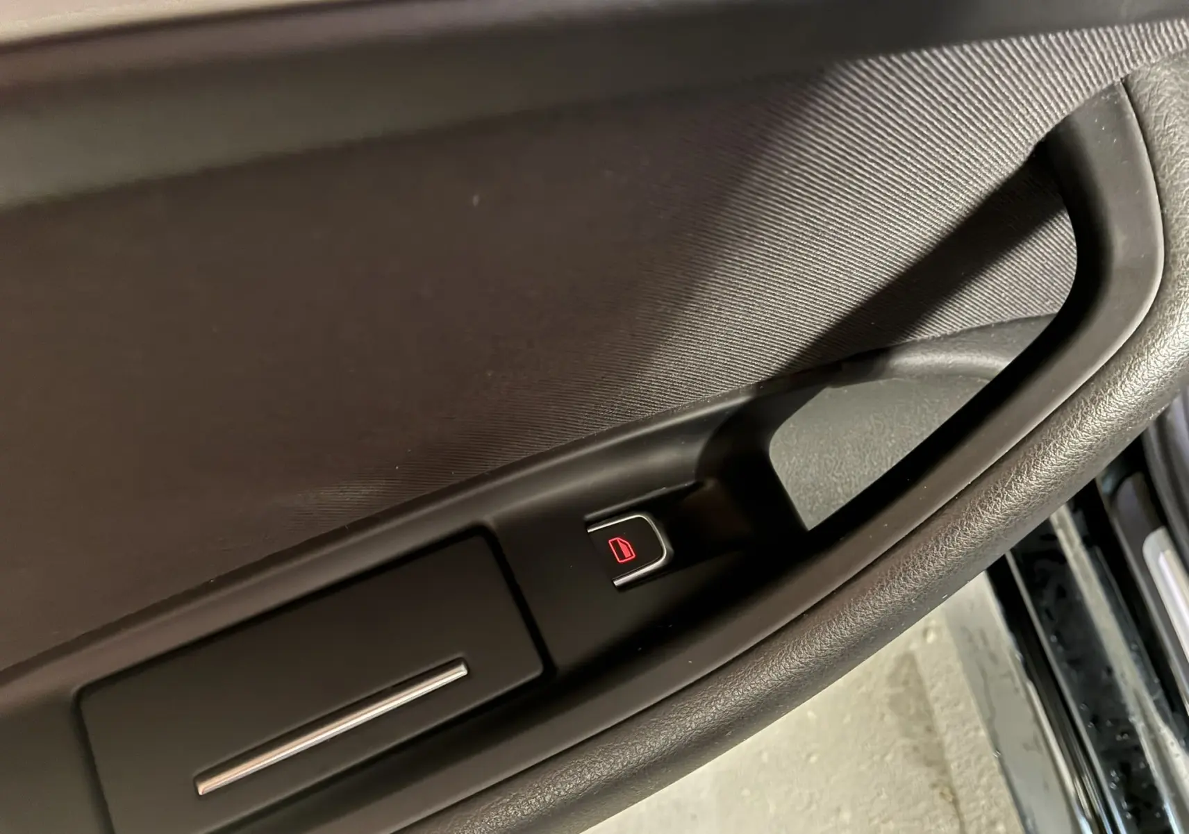 Bouton de verrouillage électrique sur la poignée intérieure côté gauche d'une Audi A6 Avant noire de 2017.