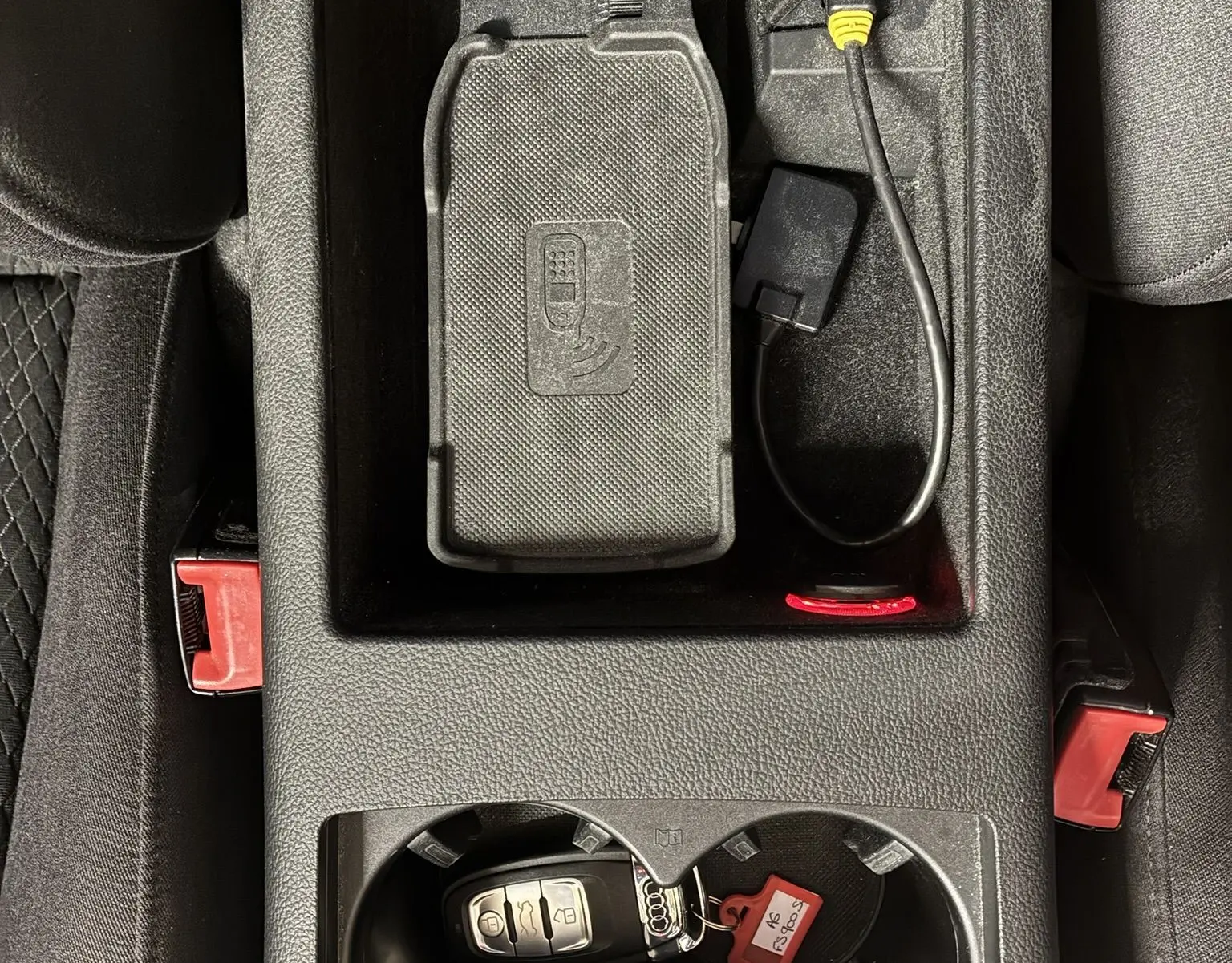 Vue plongeante sur la console centrale noire d'une Audi A6 Avant 2017 avec clé et accessoires de connexion.