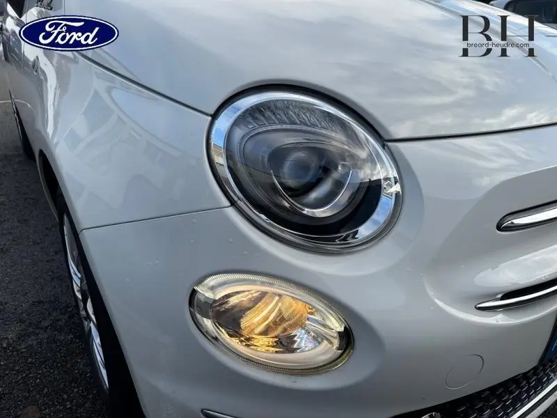 Gros plan sur le phare avant gauche d'une FIAT 500 blanche Bossa Nova avec feu de jour LED allumé.