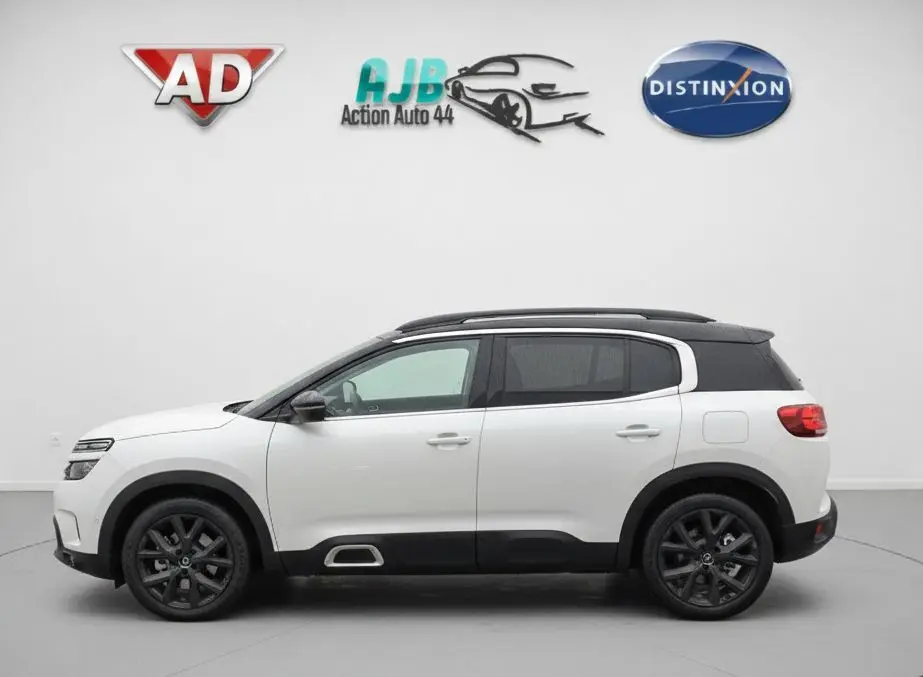 Vue de profil côté gauche du Citroën C5 Aircross blanc nacré avec toit noir et jantes noires en studio.