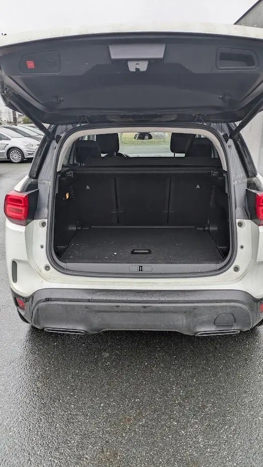 Vue arrière du coffre ouvert d'un Citroën C5 Aircross blanc nacré, montrant l'espace de chargement vide.