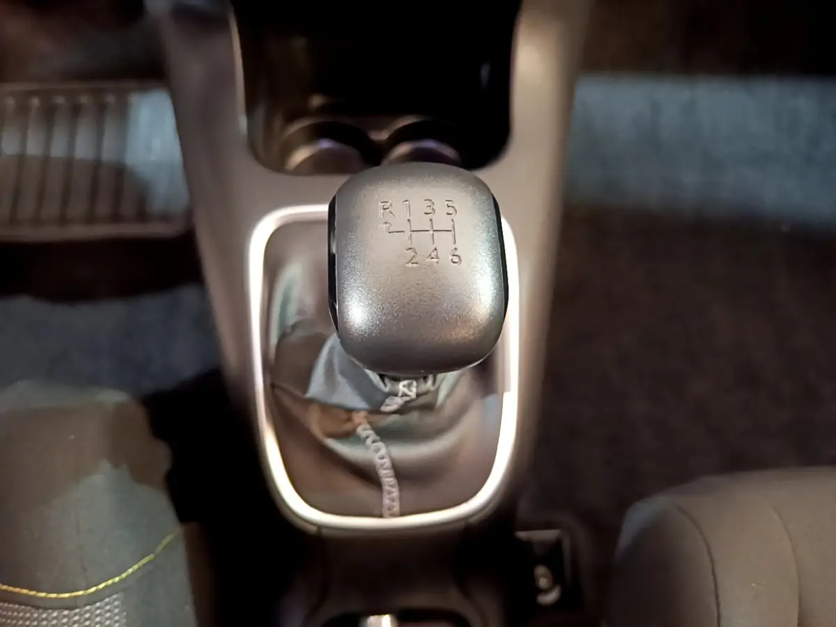 Le levier de vitesses manuel gris de la CITROEN C3 blanche, vu de dessus au centre de l'habitacle.