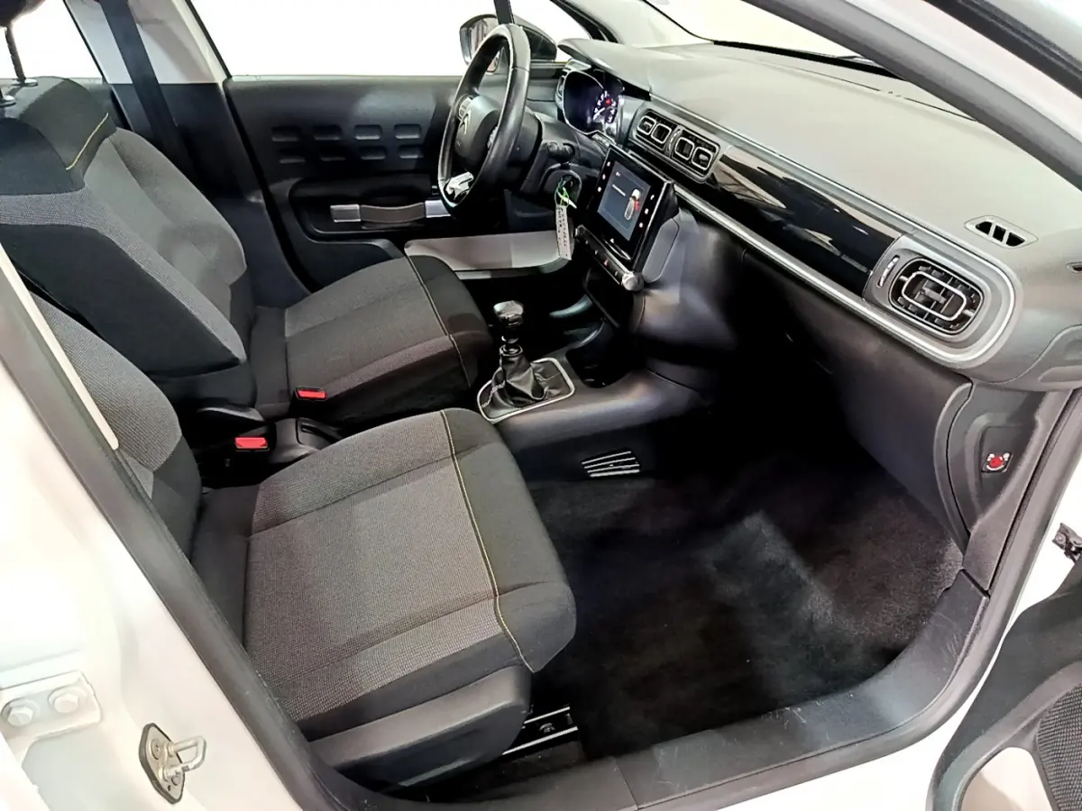 Intérieur avant droit de la Citroën C3 blanche 2019, montrant sièges gris, volant cuir et écran tactile central.