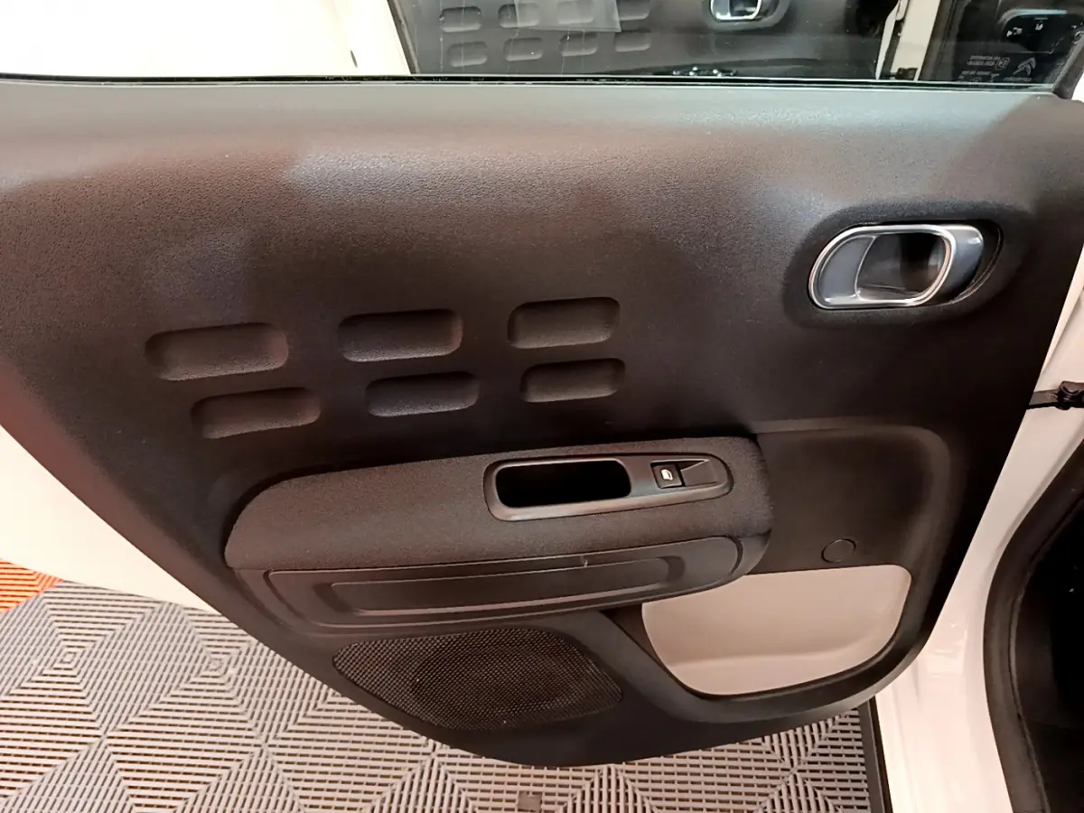 Vue rapprochée de la porte avant droite blanche de la Citroën C3 avec panneau noir et poignée argentée.