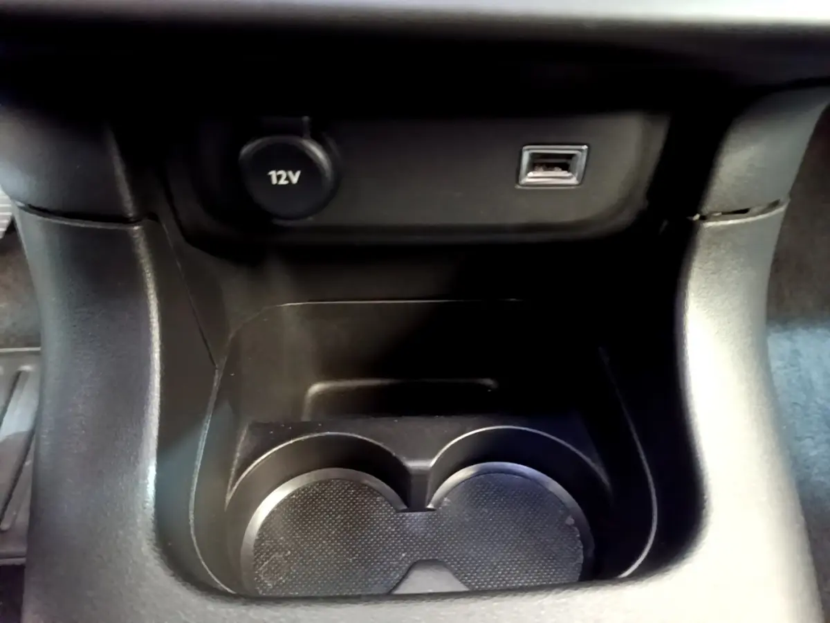 Gros plan sur la console centrale noire de la Citroën C3 2019 avec prise 12V et port USB au-dessus des porte-gobelets.