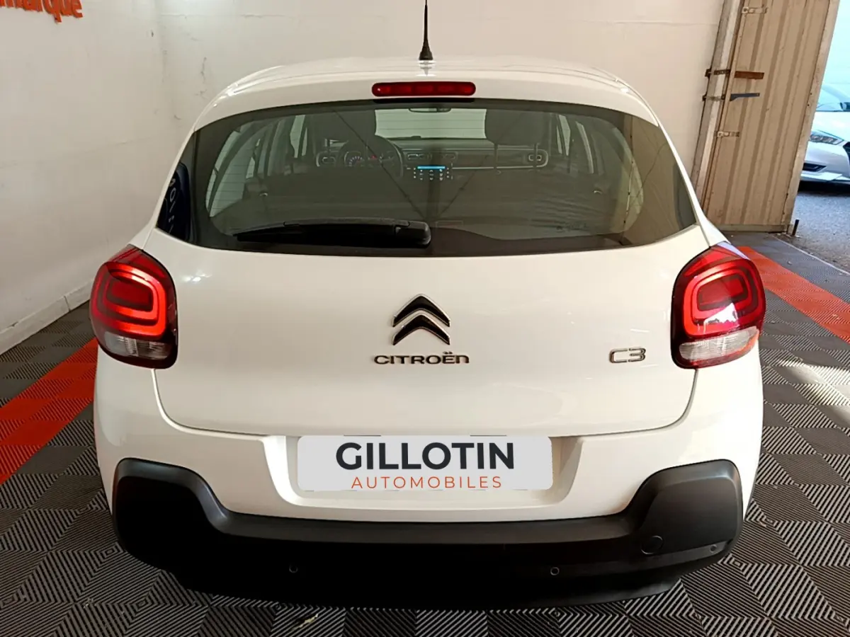 Vue arrière d'une Citroën C3 blanche de 2019, avec feux arrière allumés et pare-chocs noir contrastant.