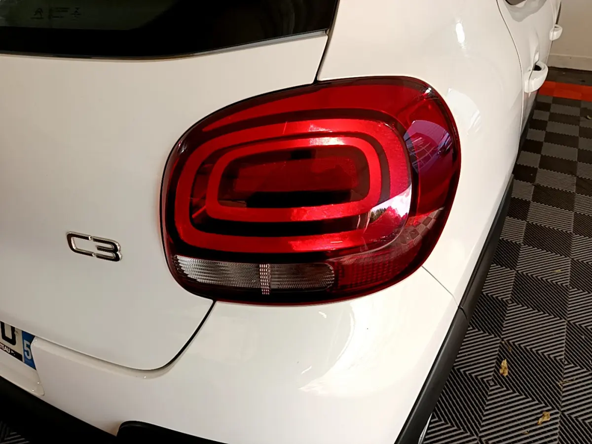 Gros plan sur le feu arrière droit rouge d'une Citroën C3 blanche de 2019, avec logo C3 visible sur le coffre.