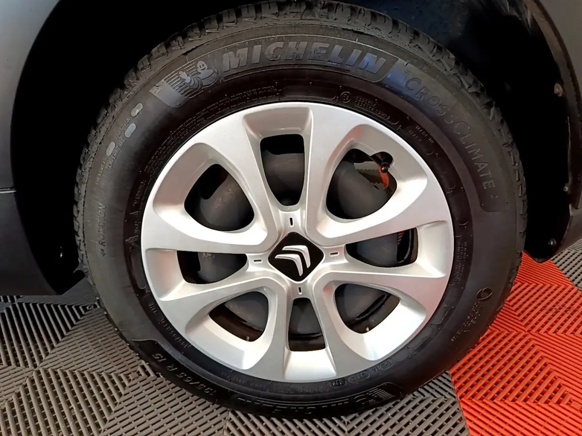Gros plan sur la roue avant droite d'une Citroën C3 blanche avec jante alliage et pneu Michelin CrossClimate.