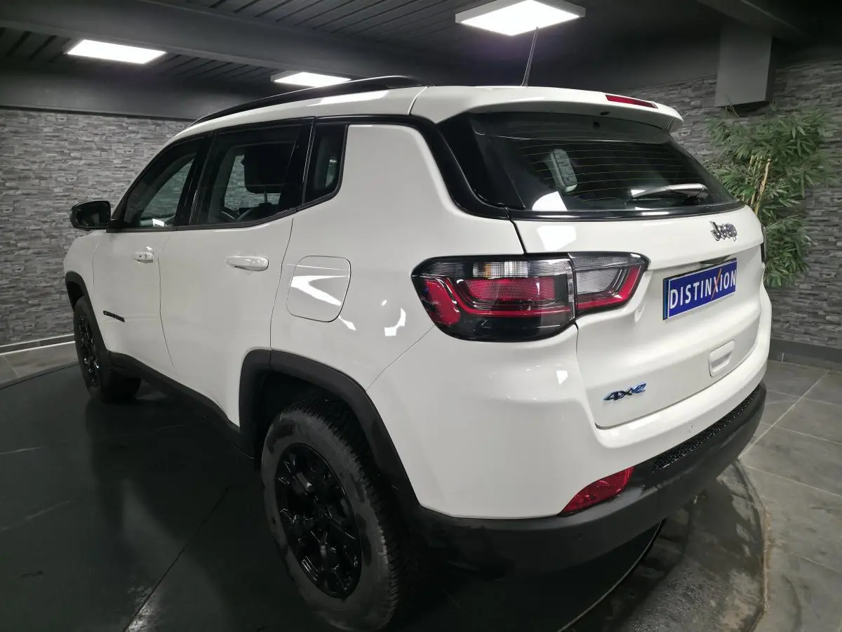 Vue 3/4 arrière droite du Jeep Compass blanc 2024 avec jantes noires et badges 4xe eAWD visibles.