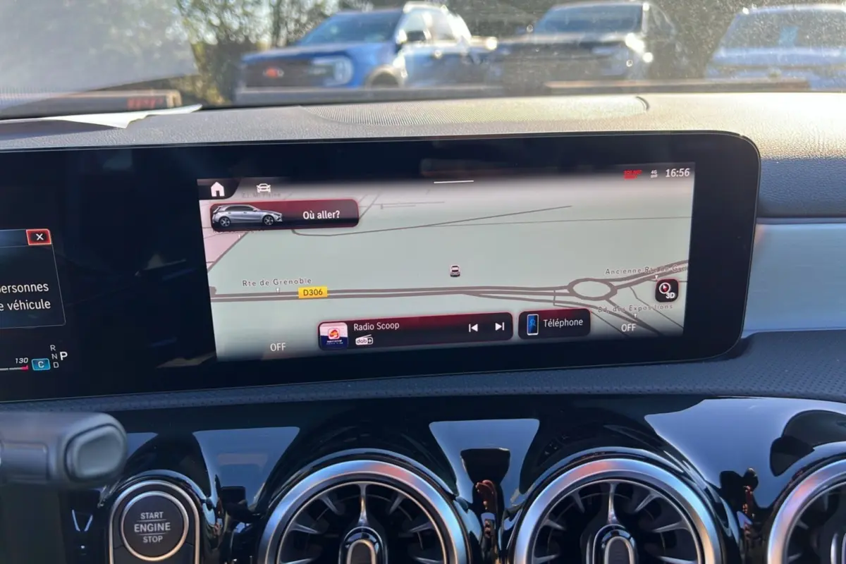 Vue intérieure du tableau de bord de la Mercedes Classe A 200D Exclusive Design avec écran tactile GPS et aérateurs ronds noirs brillants.
