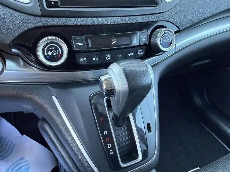 Gros plan sur la console centrale avec levier de vitesse automatique du Honda CR-V 2017, intérieur noir et détails chromés.