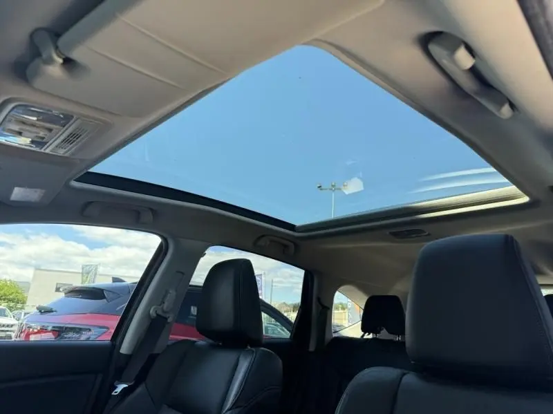 Vue intérieure du toit ouvrant panoramique d'un Honda CR-V rouge métal 2017, avec sièges avant en cuir noir visibles.