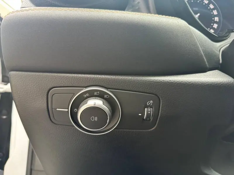Gros plan sur la commande des phares et réglage de luminosité dans l’habitacle noir de l’Alfa Romeo Tonale blanc Monterosa.