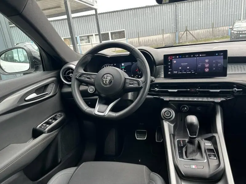 Vue intérieure côté conducteur de l'Alfa Romeo Tonale 2025 avec volant cuir, écran tactile large et levier de vitesse automatique.