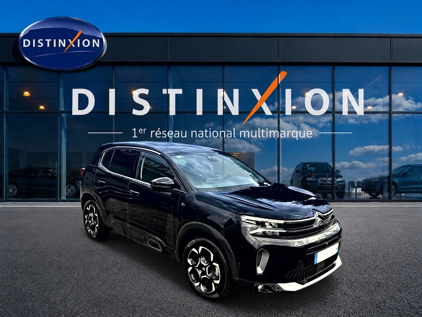 Citroën C5 Aircross noir vue 3/4 avant droit, avec jantes alu et calandre distinctive, devant un showroom Distinxion.