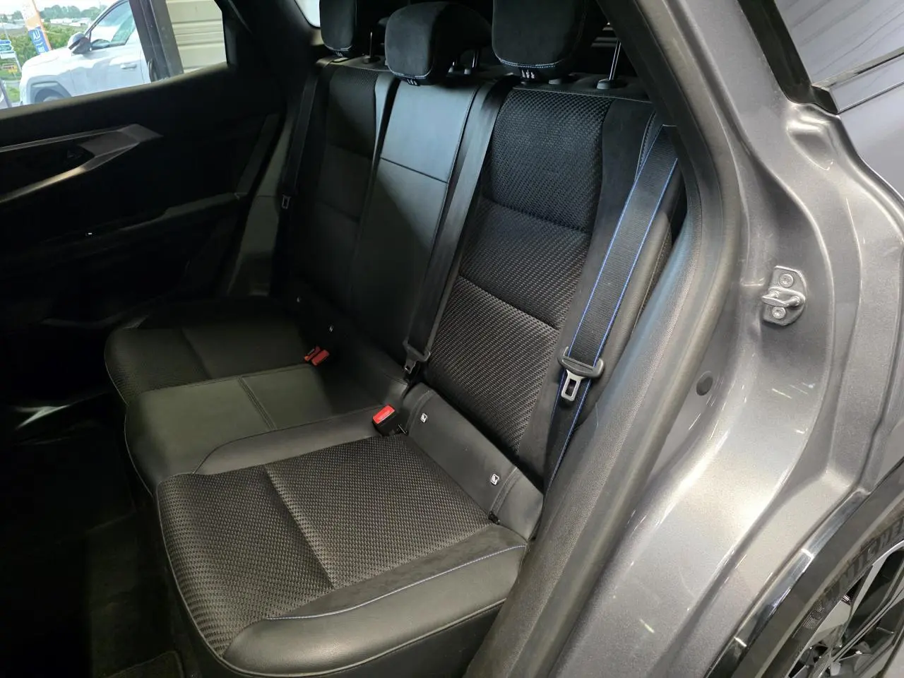 Vue intérieure côté droit sur la banquette arrière mixte tissu et Alcantara noire avec surpiqûres bleues du Renault Austral gris foncé.