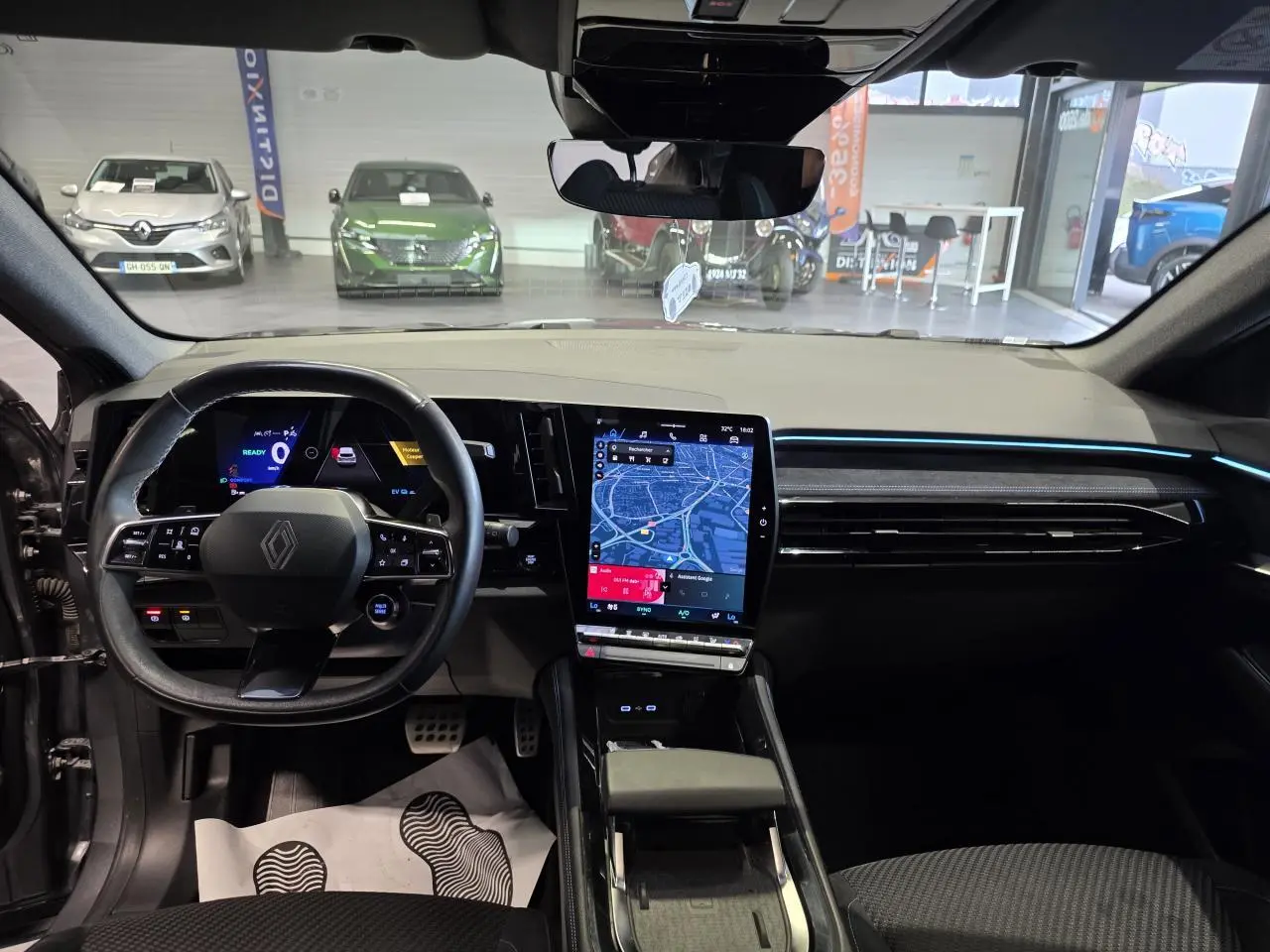 Vue intérieure avant du Renault Austral gris foncé, mettant en valeur le volant multifonction et l'écran tactile central vertical.