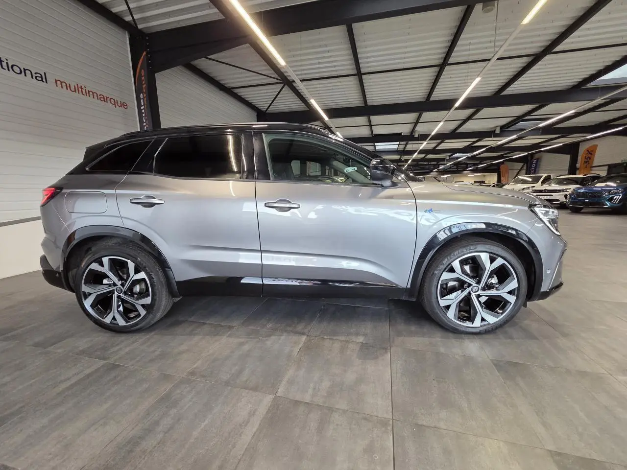 Profil droit du Renault Austral 2024 gris foncé avec toit noir étoilé et jantes alliage 20 pouces diamantées.