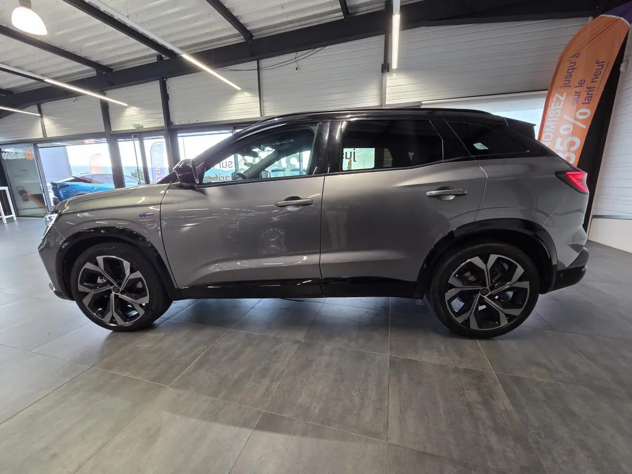 Profil droit du Renault Austral 2024 gris foncé avec toit noir étoilé et jantes alliage 20 pouces diamantées.