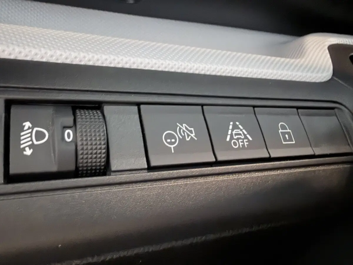 Gros plan sur les boutons de commande noirs du tableau de bord d'une Citroën C3 Aircross électrique gris foncé.