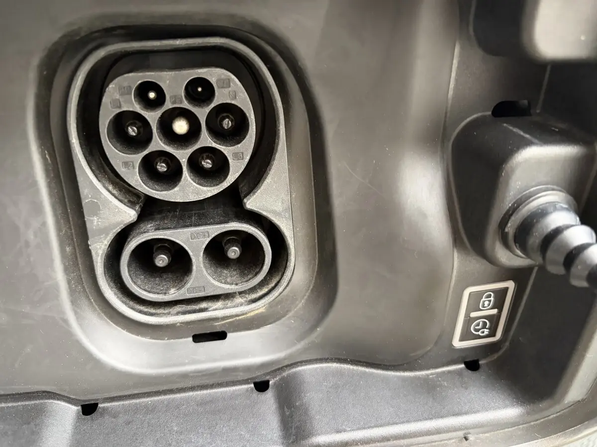 Gros plan sur la prise de charge électrique noire du Citroën C3 Aircross gris foncé, avec câble branché visible.