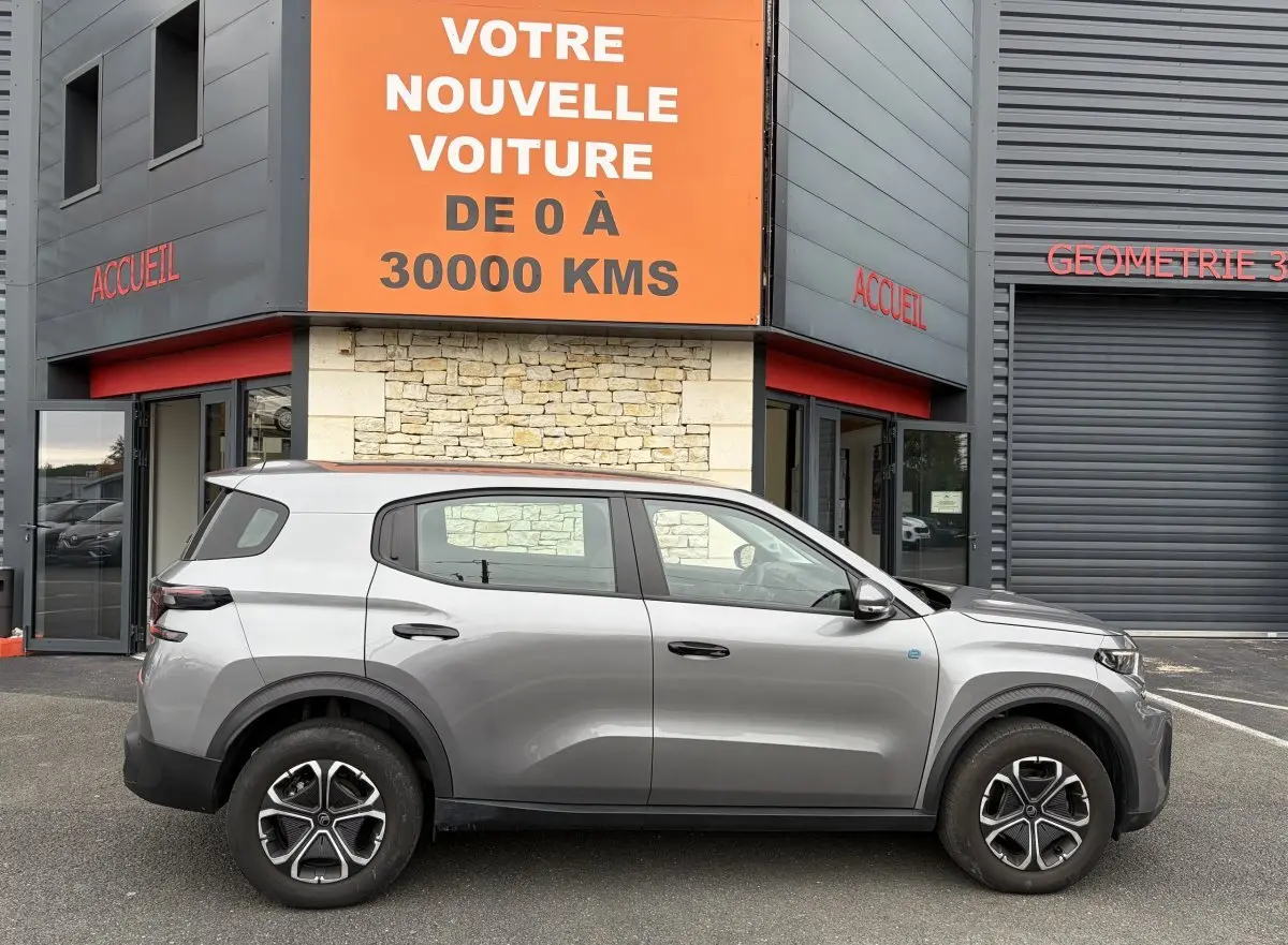 Profil côté droit d'un Citroën C3 Aircross électrique gris foncé 2025, avec jantes distinctives et détails noirs contrastants.