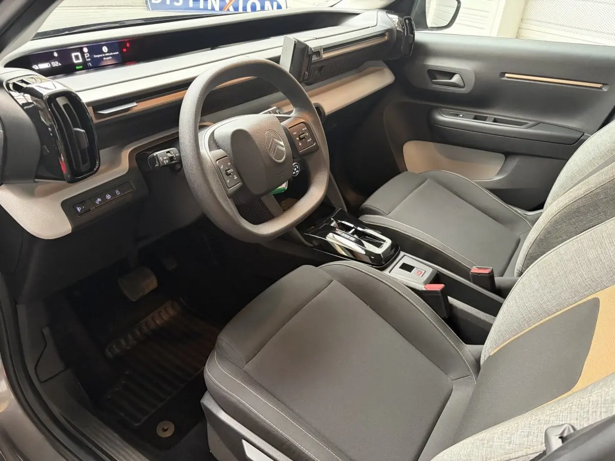 Intérieur avant droit du Citroën C3 Aircross électrique gris foncé, volant multifonctions et écran tactile visible.